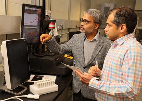 Two Professors review data on equipment in the lab