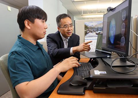 Professor and student review biomedical image on a computer screen
